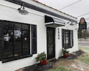 Storefront with white brick and black trimmed windows.