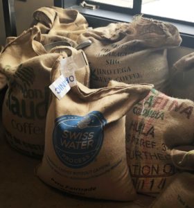  Six large burlap sacks of raw coffee beans.