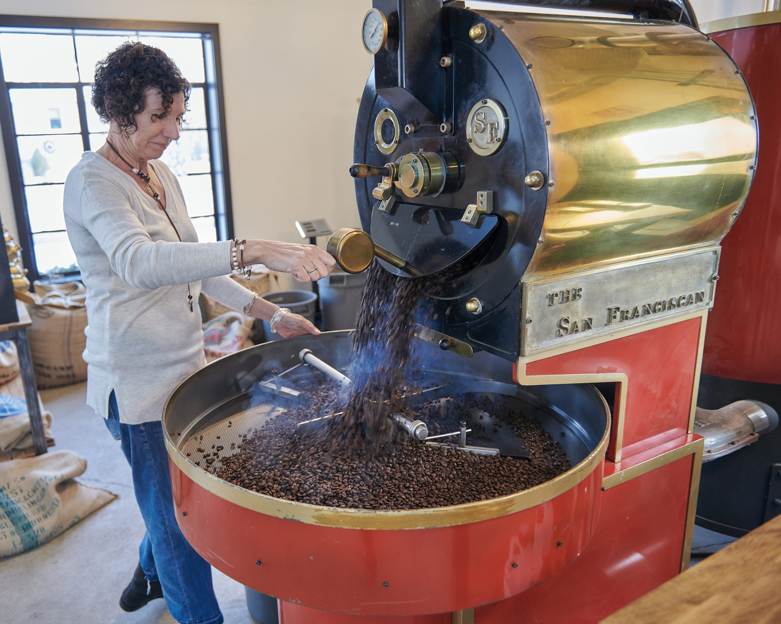 Kate stirring roasted coffee beans in the roaster.