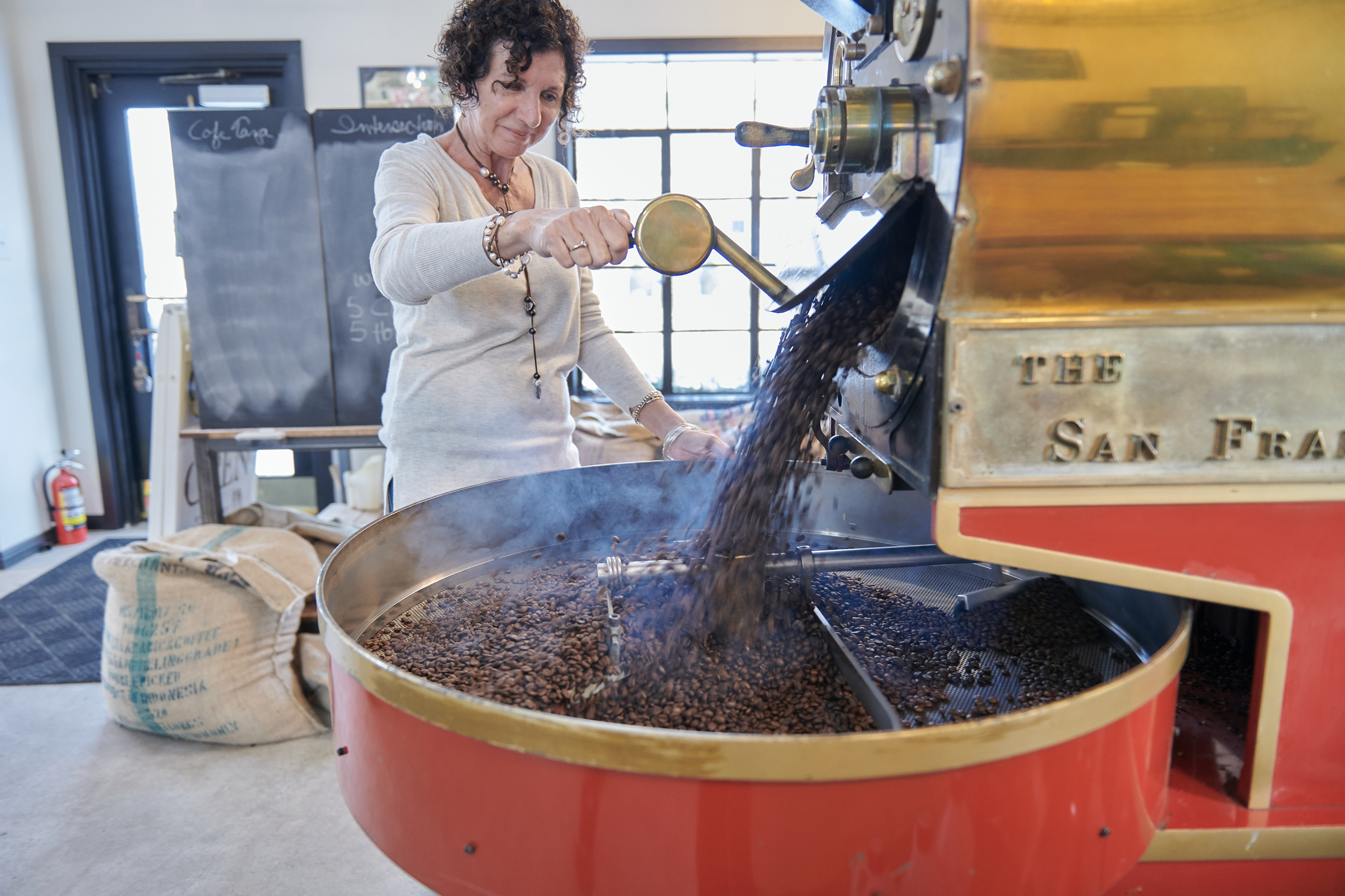 Kate pouring roasted beans from the roaster.