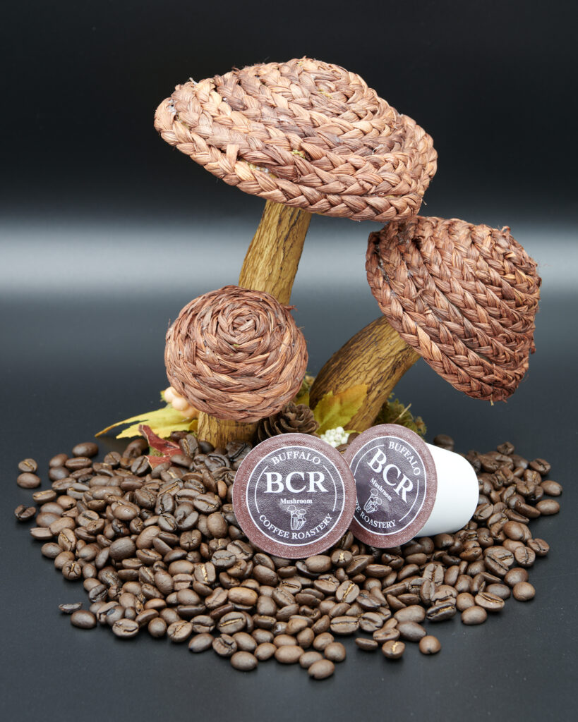 BCR K-Cups atop small mound of whole coffee beans, under woven mushroom stalks.